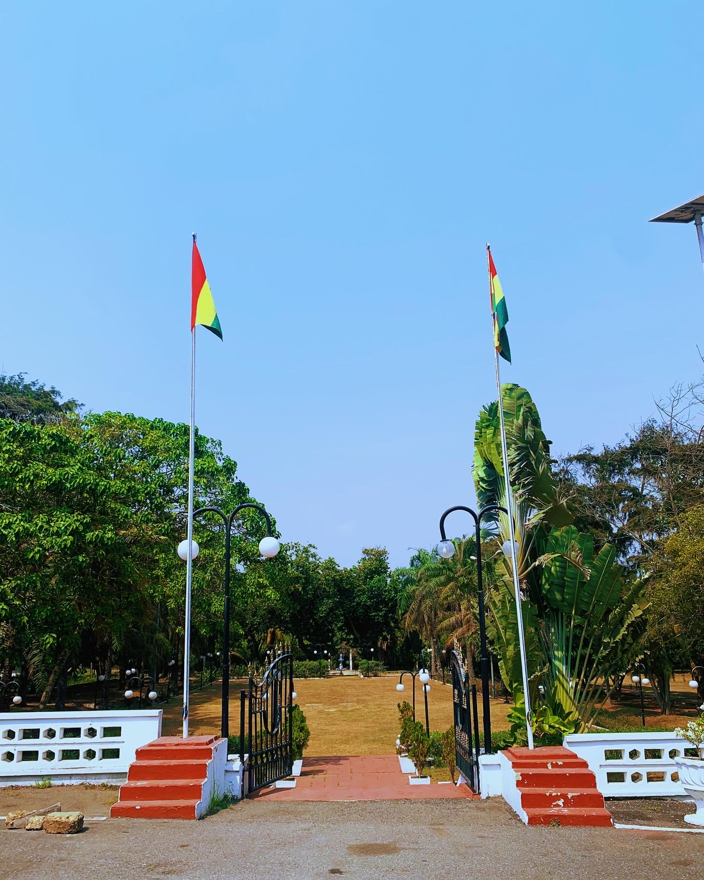 Two flags beside an open gate under a clear sky