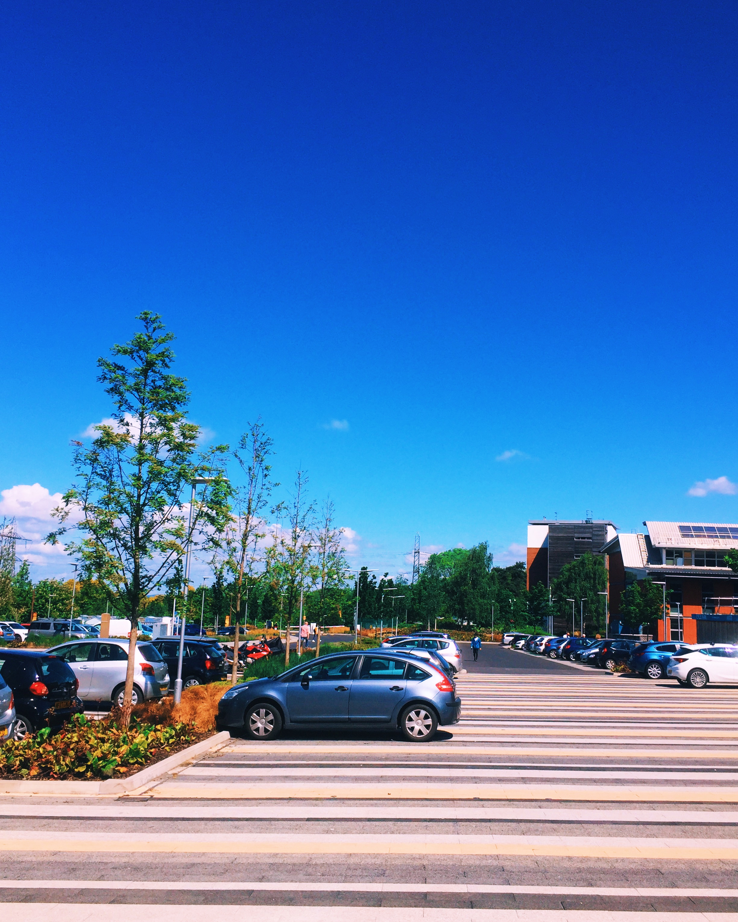 Pedestrian crossing and car park under a wide blue sky
